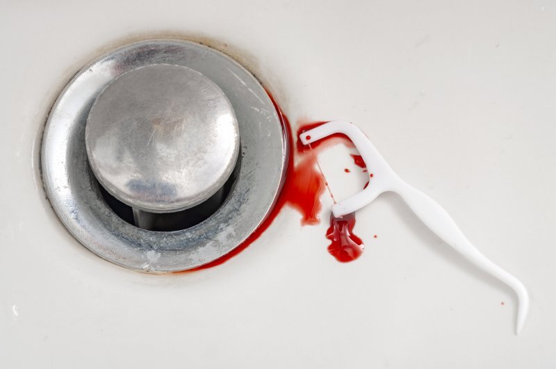 A flossing stick with blood in a sink from flossing gone wrong